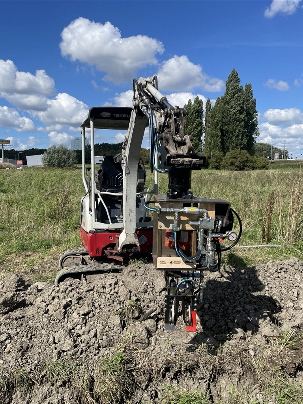 Rooibot op een minigraver tijdens een test in het veld voor het mechanisch verwijderen van elektriciteitskabels.