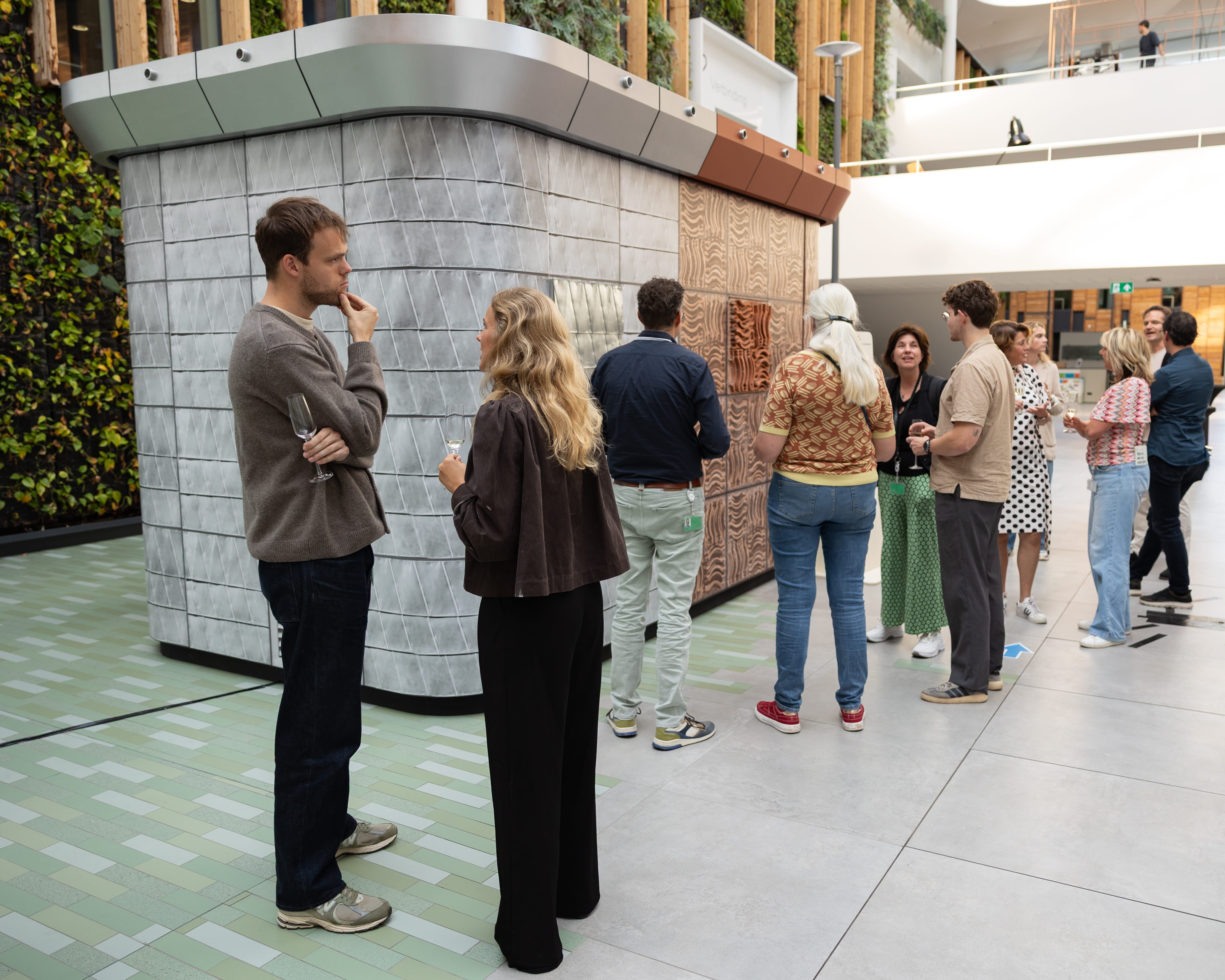 Groep mensen bekijkt een circulair elektriciteitshuisje in een moderne binnenruimte
